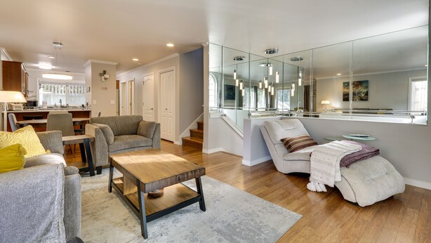 A modern living room with a sofa, armchair, and coffee table. There is a staircase leading to an upper level. - Lake Oswego Home w/ Deck 9 Mi to Downtown Portland (Lake Oswego)