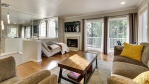 A living room with a fireplace, a sofa, a coffee table, and a large mirror. - Lake Oswego Home w/ Deck 9 Mi to Downtown Portland (Lake Oswego)