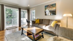 A living room with a sofa, coffee table, and a painting on the wall. - Lake Oswego Home w/ Deck 9 Mi to Downtown Portland (Lake Oswego)