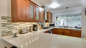 A kitchen with wooden cabinets, a microwave, and a window with a view of greenery. - Lake Oswego Home w/ Deck 9 Mi to Downtown Portland (Lake Oswego)