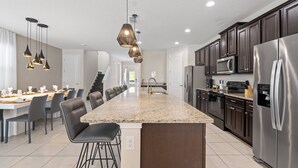A modern kitchen with a central island, stainless steel appliances, and pendant lighting. - Last Minute Disney! Private Pool, Hot Tub, Game Room & Themed Bedrooms. Book Now! #89725 (Orlando)