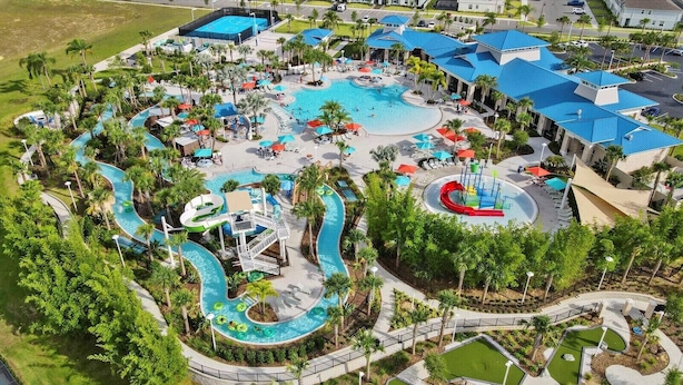 Vista aérea de un complejo turístico con varias piscinas, toboganes acuáticos y palmeras.