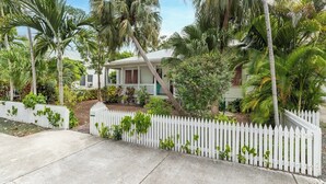 A house with a white picket fence, surrounded by palm trees and lush greenery. - Truman House (Key West)