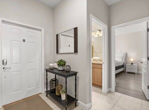 A hallway with a white door, a console table with decorative items, and a mirror.