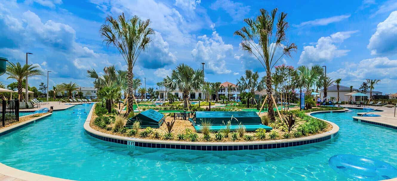 A large, circular swimming pool with multiple lanes, surrounded by palm trees and greenery.
