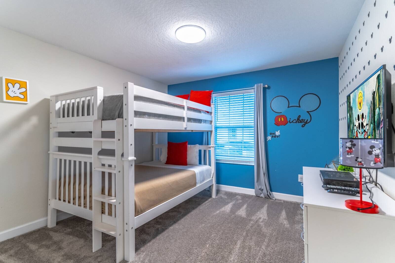 A child's room with bunk beds, a desk with a computer, and Mickey Mouse wall decals.