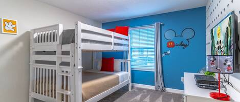 A child's room with bunk beds, a desk with a computer, and Mickey Mouse wall decals.