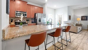 Una cocina moderna con encimeras de granito, electrodomésticos de acero inoxidable y armarios de madera.