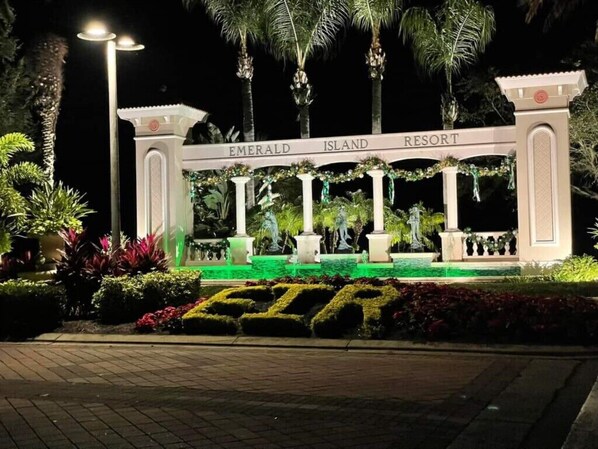 A sign for Emerald Island Resort with a well-lit entrance and a green-lit pathway.