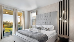Un dormitorio con una cama grande, un balcón con vistas y una lámpara moderna.
