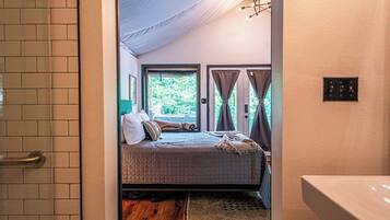 Un dormitorio con cama, ventana con cortinas, suelo de madera y una lámpara en el techo.