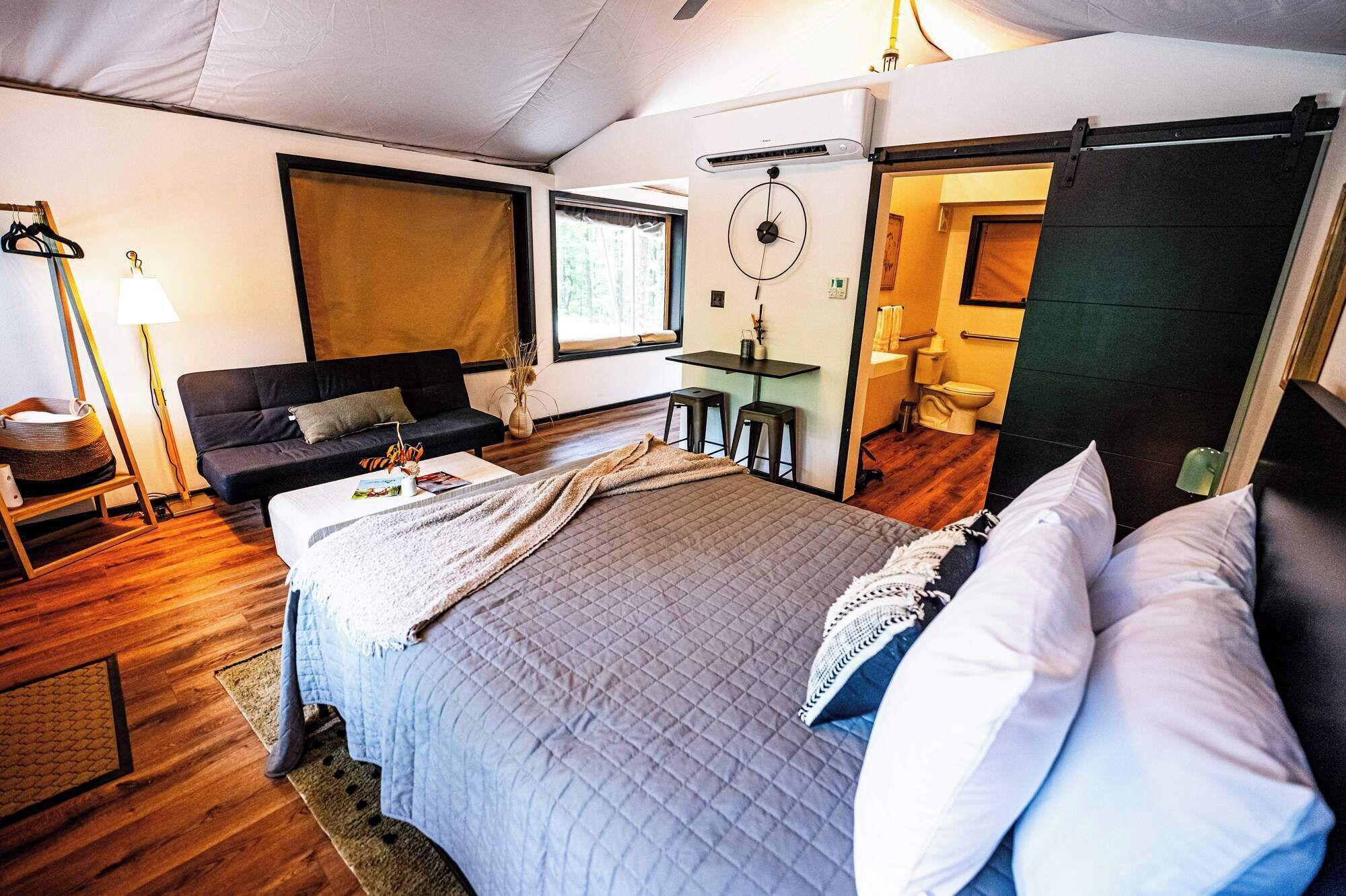 Ein gemütliches Schlafzimmer mit Bett, Sofa, Schreibtisch und eigenem Bad.
