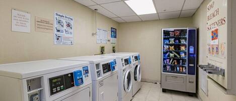 Een wasserette met meerdere wasmachines en drogers, een automaat met snacks, en borden met wasinstructies.