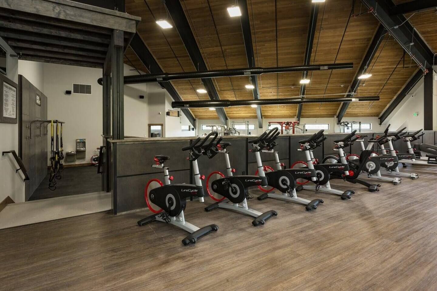 A gym with multiple stationary bikes, a wooden ceiling, and a counter with exercise equipment.
