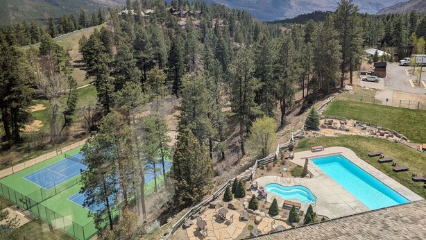 A residential area with a tennis court, swimming pool, and a view of mountains.