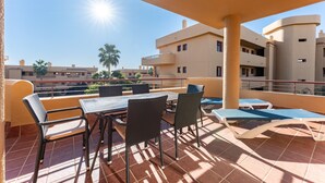Un patio al aire libre con una mesa, sillas, un toldo y vistas de edificios cercanos.