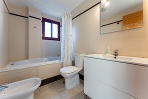 Een badkamer met een bad, toilet en wastafel.
