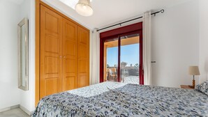 Un dormitorio con cama, armario de madera y vistas a través de un ventanal.