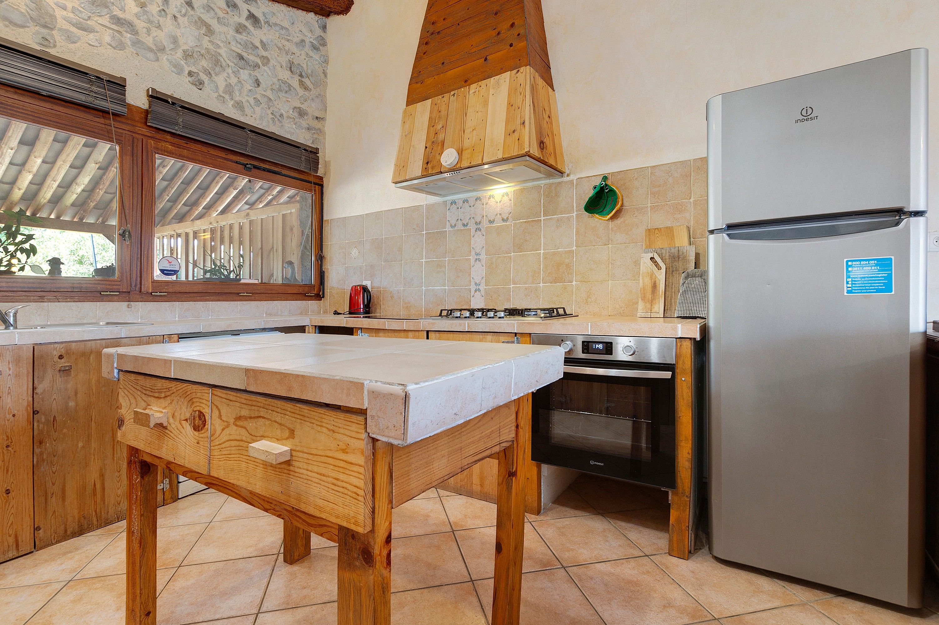 A kitchen with a wooden table, a stainless steel refrigerator, and a built-in oven.