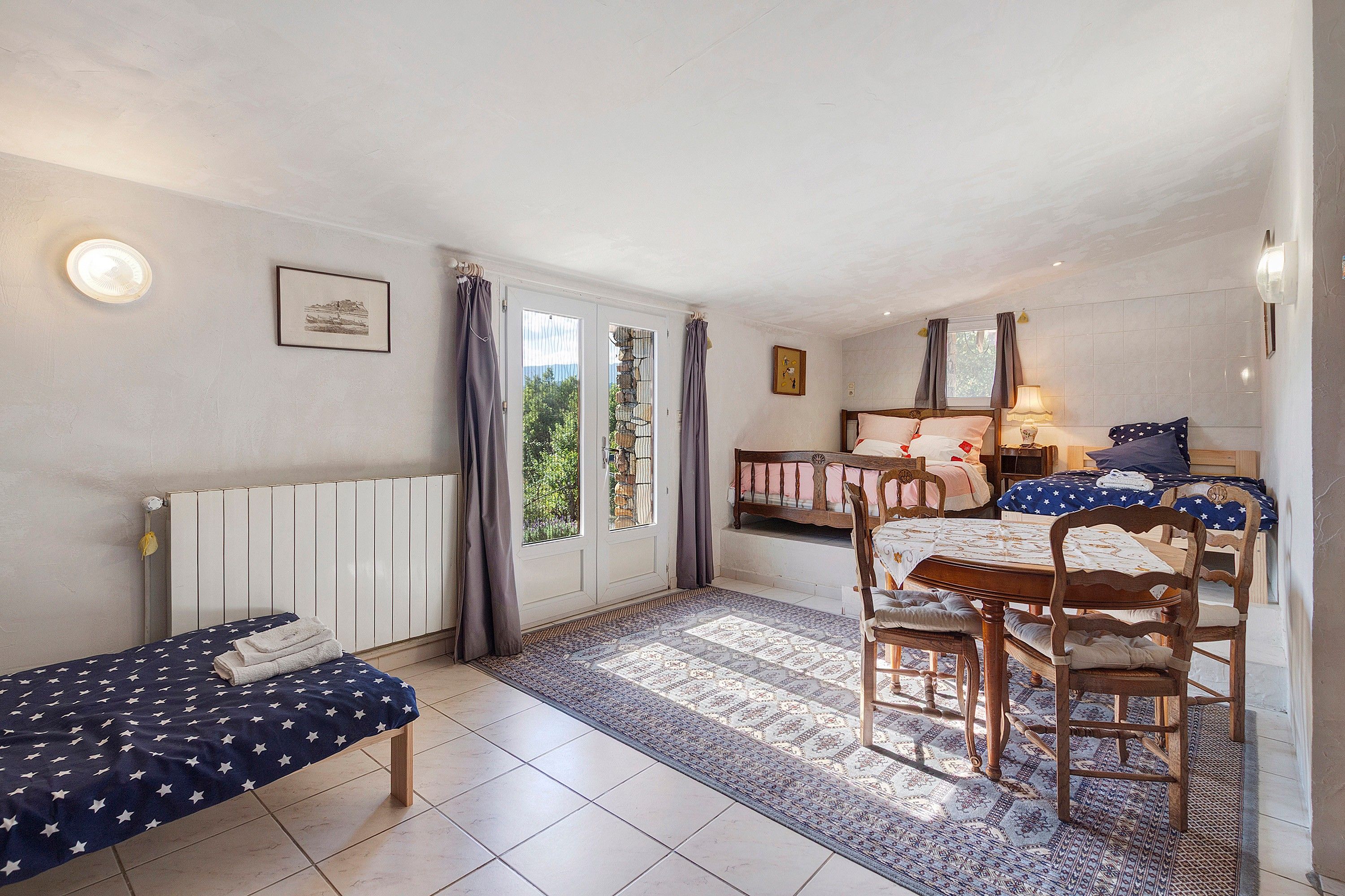 A room with a bed, a chair, a table, and a radiator.