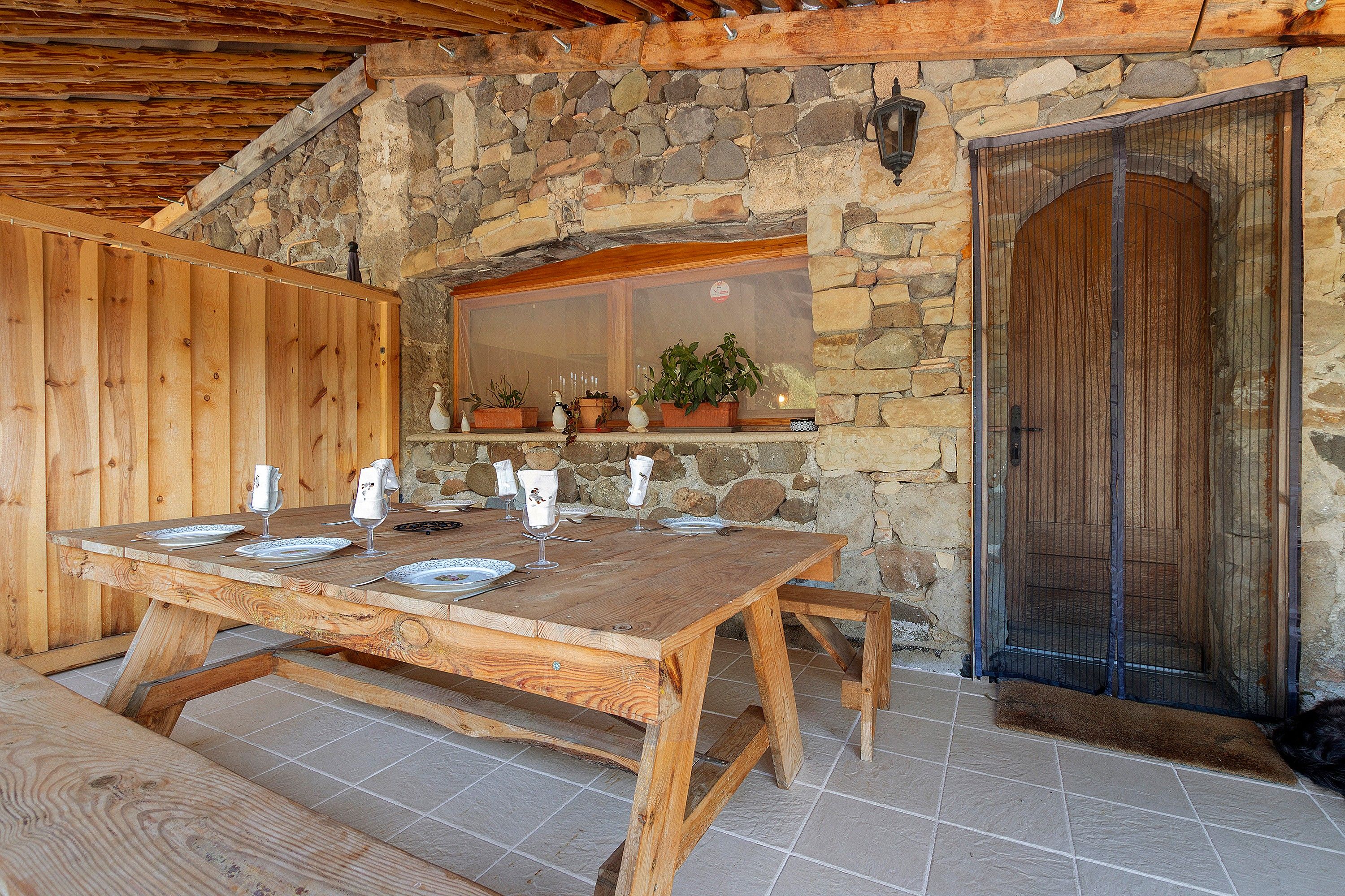A rustic wooden table set for dining with stone walls and a wooden door in the background.