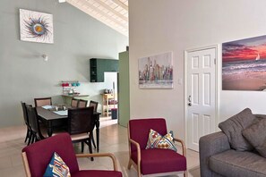 A living room with a sofa, a red armchair, and a dining area with a table and chairs.