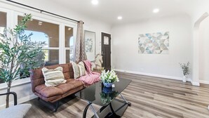 Una sala de estar moderna con un sofá de cuero marrón, una mesa de centro de vidrio y una planta en maceta.