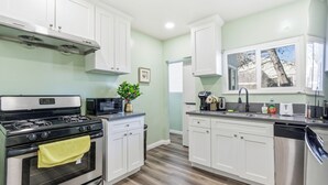 Una cocina moderna con armarios blancos, electrodomésticos de acero inoxidable y un ventanal que proporciona luz natural.