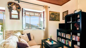 Un salon comprenant un canapé, une table basse, une bibliothèque et une grande fenêtre donnant sur l’extérieur.