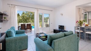 A modern living room with teal sofas, a flat-screen TV, and a dining area with a table and chairs. - 2 Bedroom Villa, Private Pool, 100m to Beach, Loggos (Loggos)