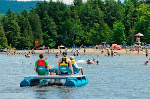 Guests can enjoy a serene lakeside experience with access to paddle boats and a scenic beach area surrounded by lush trees.
