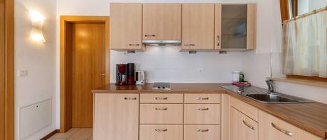 A modern kitchen with wooden cabinets, a stainless steel sink, and a window with a curtain.