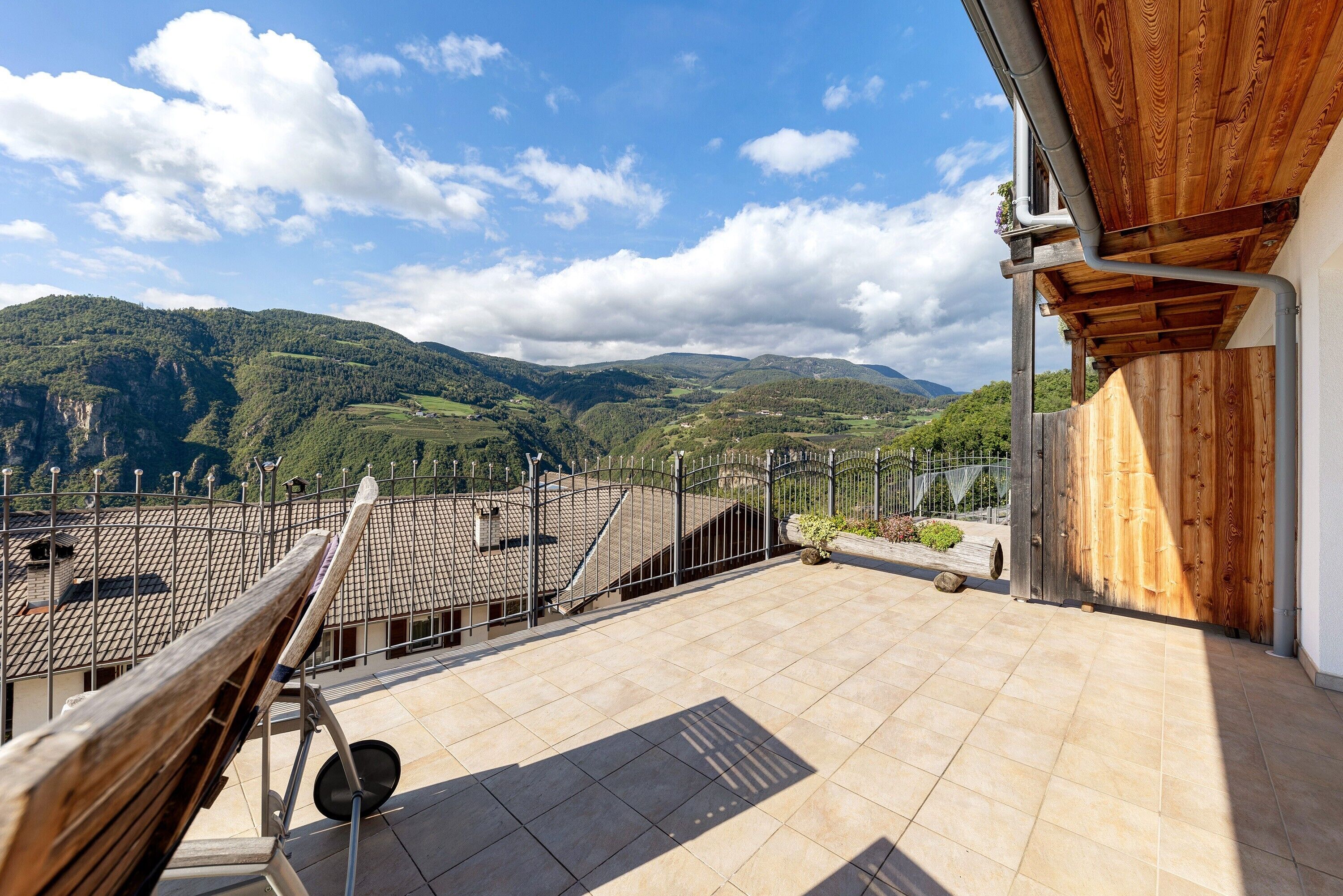A rooftop terrace with a view of green hills and a clear sky.