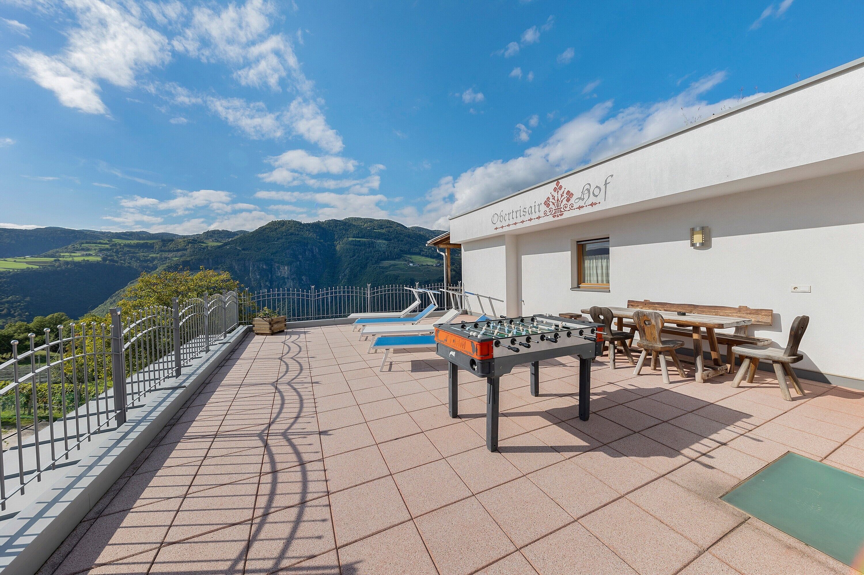 Una terraza con mesa de fútbol de mesa, asientos al aire libre y vistas a las montañas.