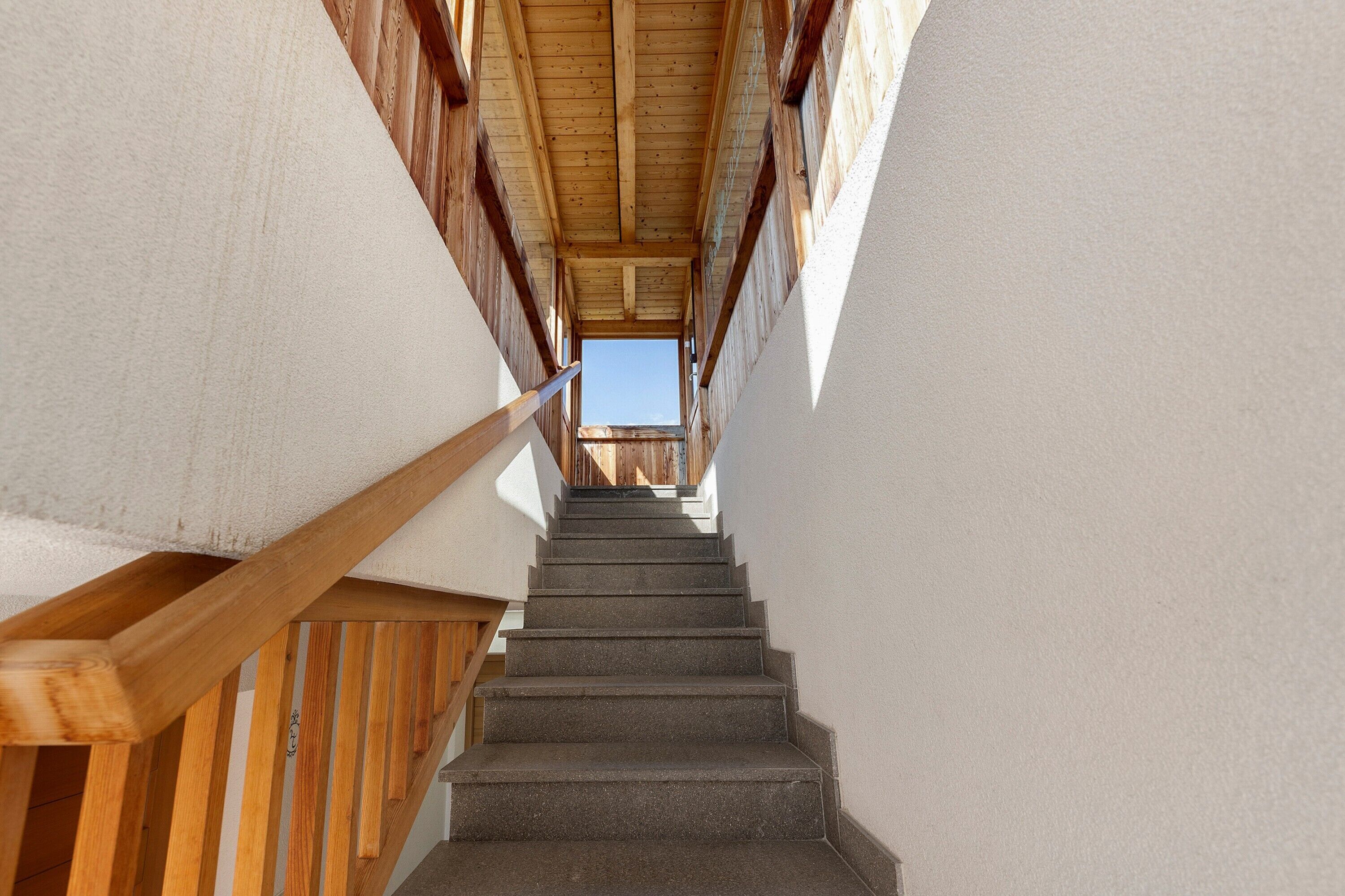 Una escalera con barandillas de madera y una vista del cielo en la parte superior.