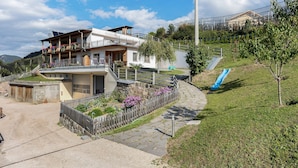 A two-story building with a balcony, a slide, and a stone pathway.