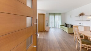 A modern living room with a wooden floor, a dining table, and a sofa.