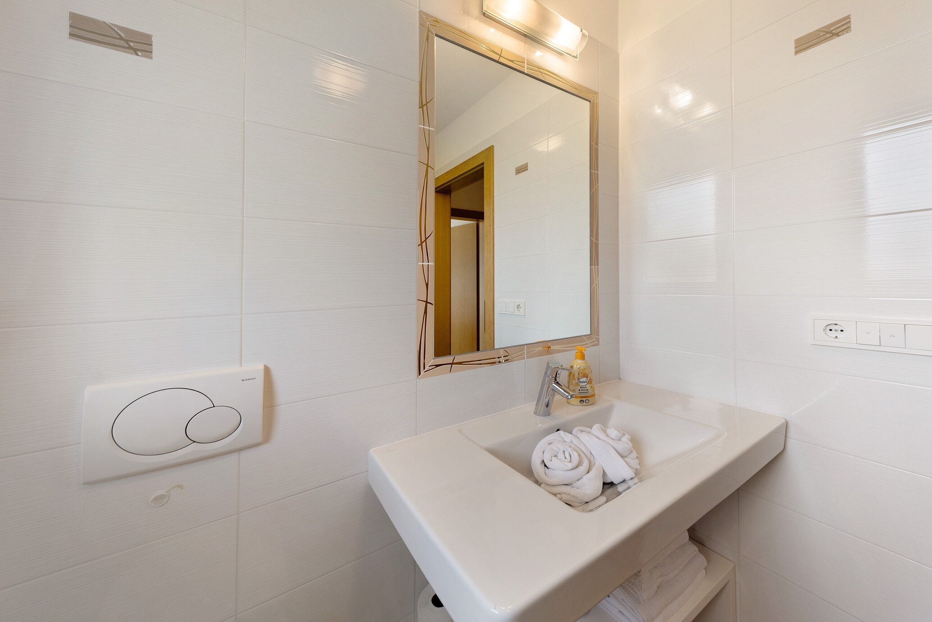 A bathroom with a white sink, a mirror, and a towel rack.