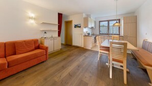 Una cocina moderna con armarios de madera, un comedor con banco y un sofá.