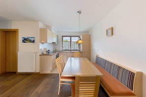 Una cucina moderna con un tavolo e una panca di legno, una lampada a sospensione e una finestra con vista.