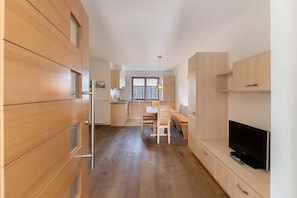 Una cucina moderna con mobili in legno, un'area pranzo con tavolo e sedie, una TV e un'ampia finestra.