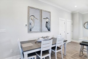 A dining area with a table, chairs, and two wall-mounted paintings of birds.