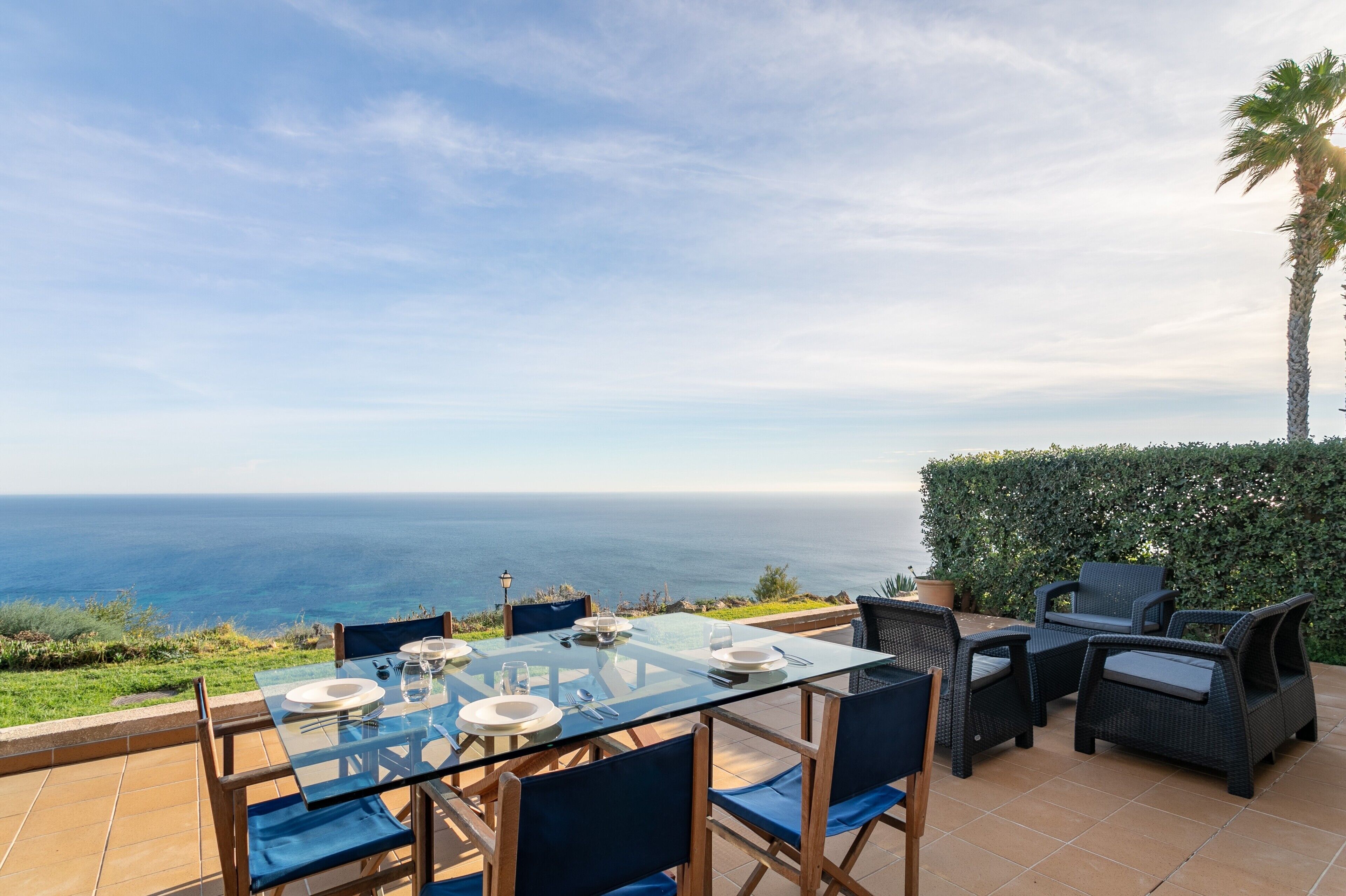 Un coin repas avec une table et des chaises en verre, offrant une vue panoramique sur l’océan.