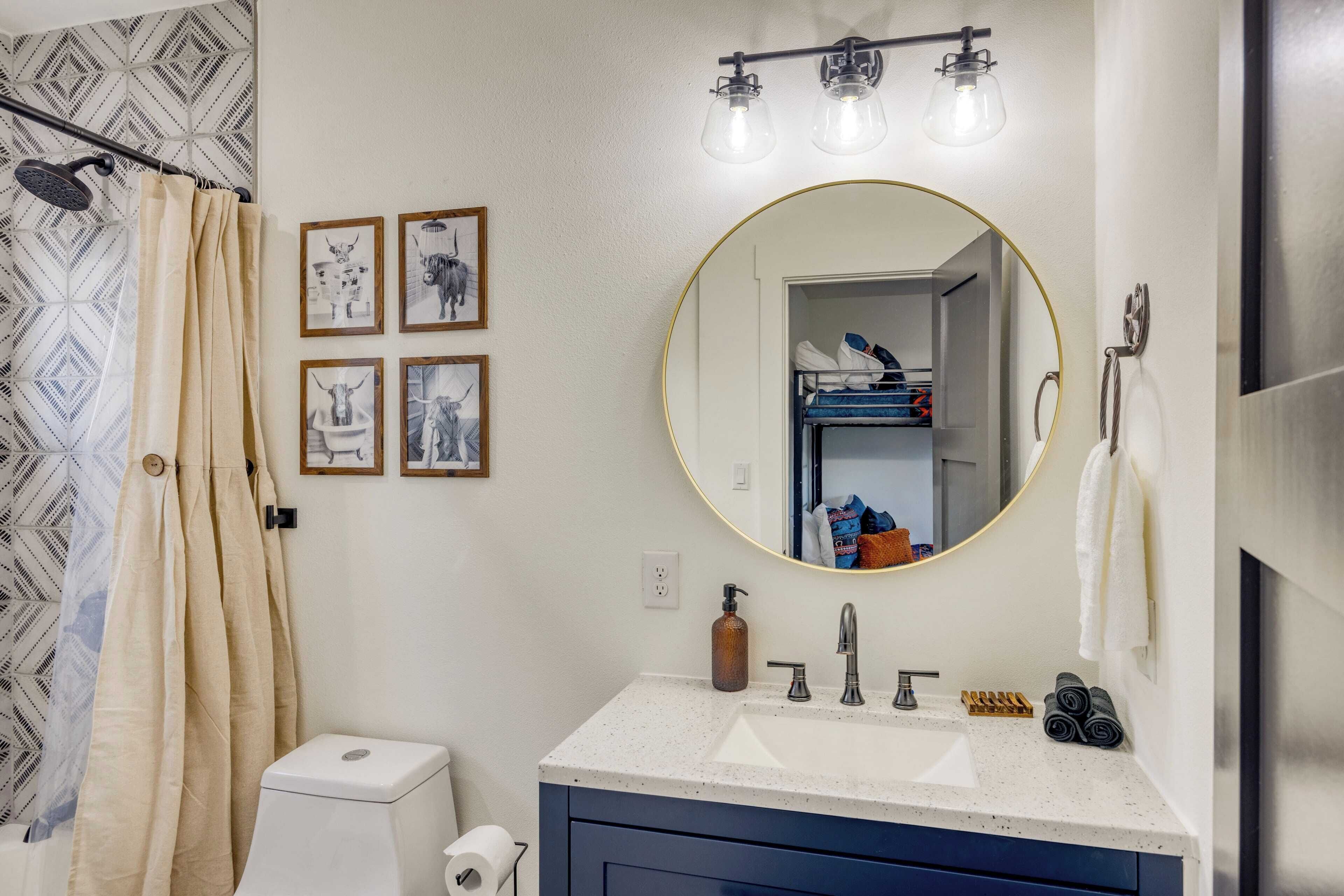 A bathroom with a white sink, a round mirror, and a shower curtain.