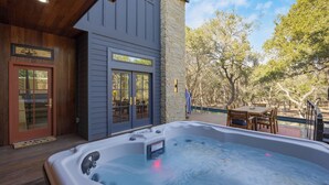 Ein Whirlpool auf einer Holzterrasse mit einer Steinwand und einer Tür mit Glasverkleidung.
