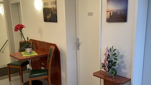 Une chambre d’hôtel avec une table à manger, des chaises, une petite plante et un tableau au mur.