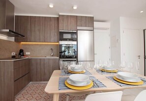 A modern kitchen with built-in appliances, a dining area with a table set for four, and a patterned floor.