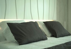 A bed with two pillows and a textured blanket.