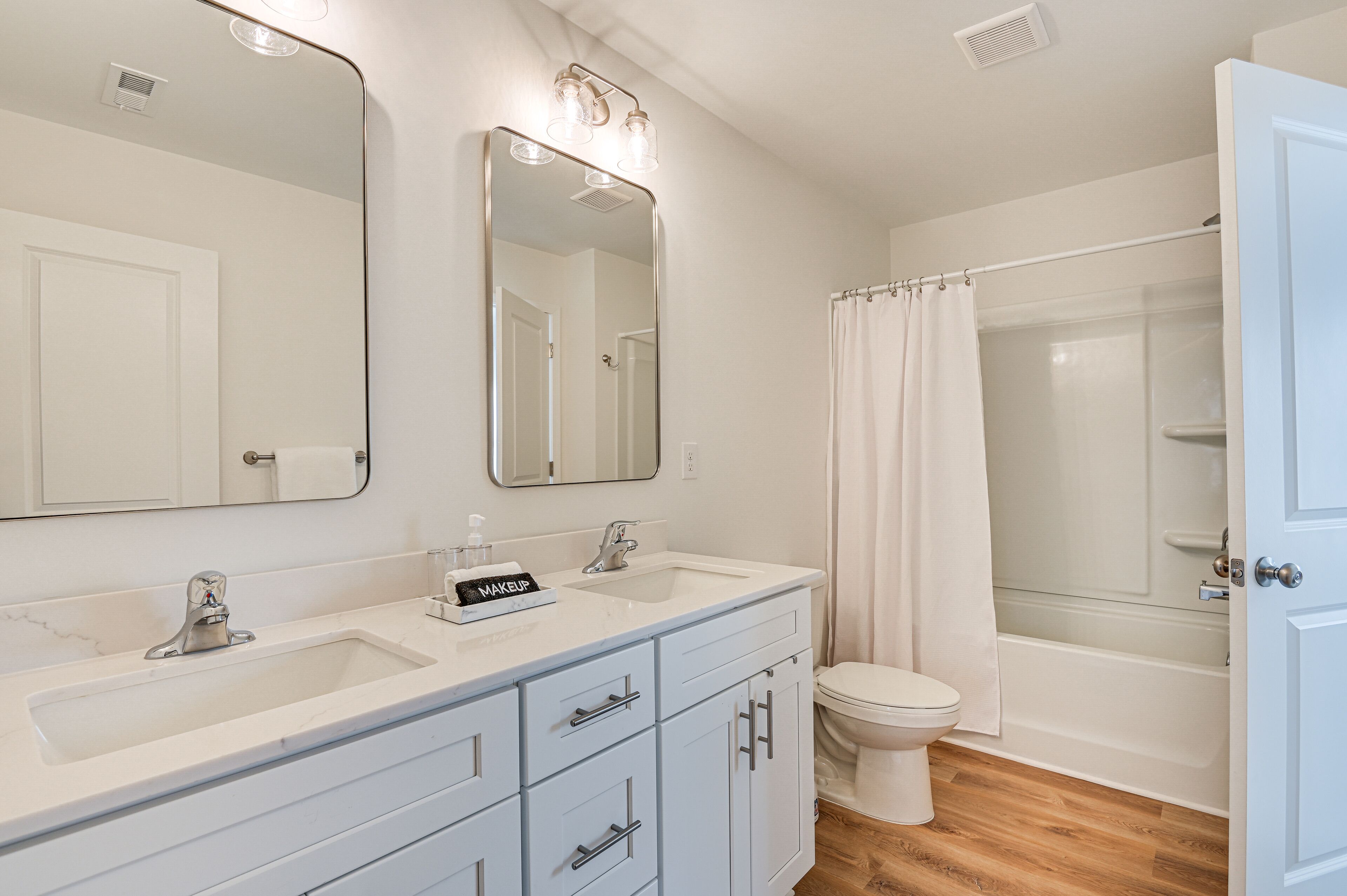 Une salle de bain avec un meuble-lavabo à deux vasques, des toilettes et une douche à parois de verre.
