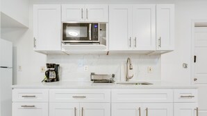 A kitchen with white cabinets, a built-in microwave, a coffee maker, and a toaster. - Ludlow Townhome: 3 Mi to Okemo Mountain! (Ludlow)
